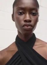 Top negro entallado sin mangas, con cuello halter cruzado.
