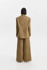 Blazer amplio de silueta cruzada, color camel/tostado, con solapas y cierre frontal de doble botonadura con botones oscuros. Presenta bolsillos con solapa.