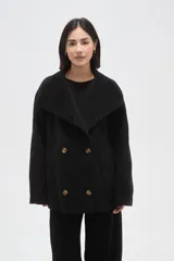 Tapado de paño negro con cuello solapa amplio y cierre frontal cruzado de doble botonadura. Presenta un corte holgado y mangas largas.