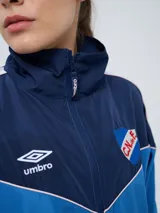 Campera deportiva Umbro del Club Nacional de Football, modelo Sky para mujer. Diseño en tonos azul marino y celeste con detalles en blanco y líneas finas rosadas, cuello alto, cierre frontal y bolsillos.