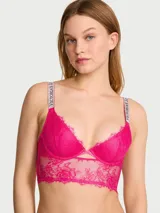 Bralette de encaje color fucsia, con aros, diseño largo estilo longline, escote pronunciado en V y tirantes brillantes con logo de pedrería.