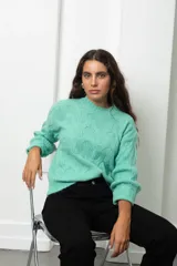 Buzo de lana color verde menta con diseño de tejido trenzado en relieve, cuello redondo y mangas largas con puños ajustados.