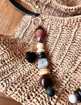 Colgante decorativo para bolso o llavero, compuesto por una cadena metálica con un conjunto de cuentas de diferentes formas, colores y texturas, incluyendo piedras naturales y cuentas de madera.