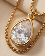Collar de cadena fina dorada con dije colgante en forma de gota con piedra transparente engastada.