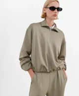 Jersey verde militar con cuello alto y cierre frontal parcial de cremallera, de manga larga y diseño holgado.