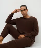 Pijama largo de dos piezas confeccionado en tejido fleece de tacto suave. Incluye una remera de cuello redondo con mangas largas y puños ajustados, y un pantalón tipo jogger con cintura elástica, cordón de ajuste y bolsillos laterales.