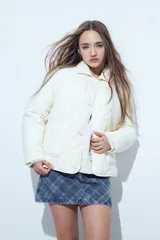 Campera acolchada de color negro con diseño capitoneado, cierre frontal con botones y cuello clásico.
