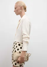 Minifalda color crema con estampado de lunares negros, de tejido satinado y corte recto.