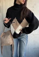 Polerón de tejido grueso con cuello alto, diseño de rombos en tonos negro, beige y blanco, y mangas largas con puños ajustados.