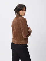 Campera de cuero gamuzado en color marrón, con diseño tipo trucker, cuello camisero, cierre frontal con botones metálicos y bolsillos con solapa en el pecho.