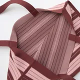 Bolso tipo tote grande de diseño estructurado, con patrón de rayas horizontales en tonos bordó y rosado, y doble asa superior de hombro.