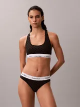 Bombacha clásica estilo bikini de Calvin Klein en color negro con monograma estampado en toda la prenda. Cuenta con una pretina elástica blanca con el logo de la marca en contraste.