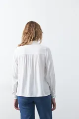 Camisa de manga larga en color celeste, con diseño de corte relajado, cuello clásico y detalle de tablas verticales en el frente.