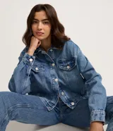 Campera de jean con corte boxy, cuello clásico, cierre frontal con botones metálicos, bolsillos con solapa en el pecho y costuras reforzadas.