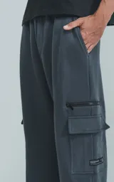 Pantalón de jogging de frisa color gris melange oscuro, con cintura y puños elásticos. Posee dos bolsillos laterales, un bolsillo trasero y un bolsillo lateral adicional con cierre.