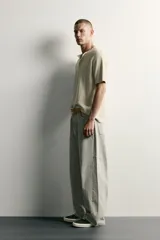 Pantalón barrel fit de mezclilla color verde militar, con efecto lavado, cinco bolsillos, cierre frontal con cremallera y botón, y detalle de pinzas en las rodillas.