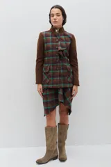 Chaqueta de lana en tono verde oliva con textura jaspeada, cuello mao y detalle de volado frontal. Presenta un corte entallado, bolsillos delanteros con solapa y cierre frontal con botones.