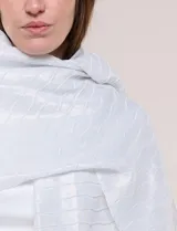 Pashmina de caída fluida color plateado, con hilos metalizados que forman líneas horizontales y terminación con flecos en los extremos.