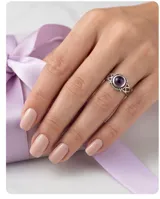 Anillo de plata 925 con piedra amatista central en corte cabujón, rodeada por un detalle de filigrana y diseño calado en los laterales del cuerpo.