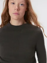 Remera de cuello alto tipo polera, confeccionada en tela rib con textura acanalada y ajuste al cuerpo. Presenta mangas largas y un pequeño bordado distintivo en la parte inferior.