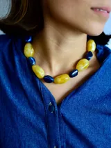Collar de cuentas grandes tipo piedra en tonos amarillo y azul marino, con cadena de acero quirúrgico ajustable.
