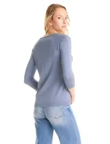 Buzo de tejido fino en color blanco, con cuello redondo y mangas raglán tres cuartos. Presenta una línea de tachas decorativas a lo largo de las mangas.