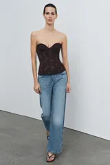 Corsé de encaje negro con escote corazón, hombros descubiertos y varillas interiores para estructura. Cuenta con cierre lateral mediante cremallera oculta.