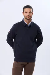 Buzo de felpa color verde oscuro, con cuello tipo polo, cierre frontal parcial con botones y bolsillos laterales. Presenta puños y ruedo acanalados.