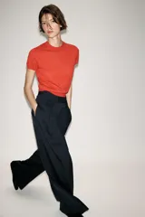 Pantalón de tiro medio con diseño wide leg, confeccionado en tejido con viscosa. Presenta un patrón de rayas diplomáticas, bolsillos laterales ocultos y detalle de pinzas pronunciadas en el delantero. Cierre frontal con cremallera, botón y ganchos metálicos.