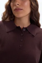 Buzo de punto color marrón, con cuello polo y cierre frontal de tres botones, de manga larga y puños ajustados.