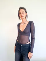 Body de manga larga confeccionado en microtul negro con detalle de strass plateado. Presenta un escote profundo en V y cierre inferior con broches.