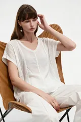 Blusa de algodón blanca de corte holgado, con cuello redondo y detalles de broderie en las mangas y costuras frontales.