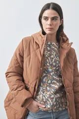 Campera puffer negra con diseño acolchado, capucha integrada y cierre frontal con botones a presión. Presenta puños elásticos y costuras decorativas en el frente.