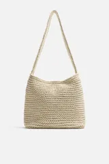 Bolso de hombro color crudo, tejido en macramé de algodón. Tiene un compartimento principal con cierre de imán y un bolsillo plano interior.