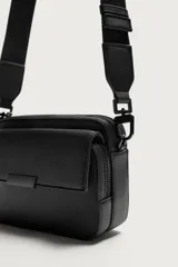 Bandolera de diseño rectangular con acabado texturizado, compartimento principal con cierre de cremallera, bolsillo frontal con solapa y asa de hombro ajustable y removible.