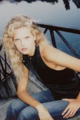 Top chaleco negro satinado con cuello halter, espalda descubierta y cierre frontal con cremallera y botón a presión ocultos por solapa.