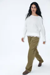 Jersey de cuello redondo y manga larga, color blanco, con bajo acabado en encaje combinado a tono.