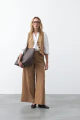 Camisa negra de corte clásico con escote en V, botones frontales y mangas largas con puños. Presenta detalles de recortes calados en la zona de los hombros.