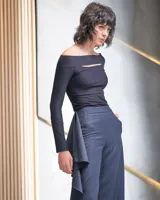 Pantalón de gabardina de lana color azul marino, de tiro alto y corte palazzo. Presenta un volante en espiral en uno de los laterales.