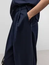 Pantalón de vestir azul marino, de corte recto, con bolsillos laterales y traseros. Se ajusta a la cintura con cinturón de cuero marrón.