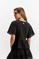 Blusa blanca de algodón con escote en V, mangas amplias y vuelo suave. Cuenta con un recorte en la cintura con frunce que aporta volumen y una caída fluida, además de una textura sutil con bordado inglés.
