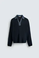Polo de punto color azul marino, de calce relajado y manga larga. Presenta un cuello solapa de tejido denim en contraste con una abertura frontal en forma de V.