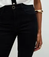 Pantalón skinny de tiro alto confeccionado en sarga de algodón con elastano. Presenta un diseño ajustado con bolsillos funcionales y detalle de botones decorativos en el ruedo.