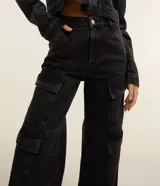 Pantalón estilo años 90 de tiro alto confeccionado en jean, con bolsillos cargo en los laterales y trabillas en la cintura.