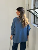 Sweater de punto color azul, con cuello redondo, corte holgado y mangas largas con puños ajustados.