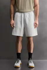 Pantalones cortos tipo jogger de corte relajado confeccionados en tejido de algodón. Presentan cintura elástica con cordón interior, bolsillos frontales en la cadera y un bolsillo trasero de plastrón.
