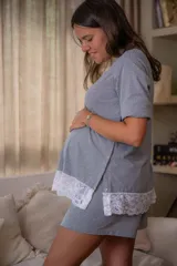 Pijama maternal de algodón gris con textura acanalada, compuesto por una remera de manga corta con broches laterales para facilitar la lactancia y detalle de puntilla blanca en el ruedo, y un short a juego con cintura ajustable.
