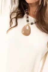 Blusa de cuello redondo con mangas largas tipo globo y puños elásticos. Presenta un diseño de textura combinada en el frente y las mangas.