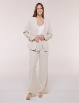 Blazer de sastrería color beige, sin solapas, con cuello en V profundo y cierre frontal de un único botón circular metálico en contraste.