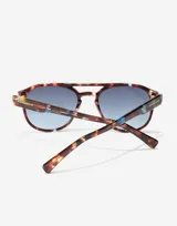 Lentes de sol Hawkers modelo Diver, con armazón de acetato en estampado carey con detalles en azul y cristales degradados en tono azulado. Diseño estilo aviador con doble puente.